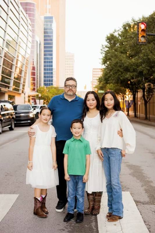 Brian Crosson with his family on a street in downtown Fort Worth, the city skyline behind them.